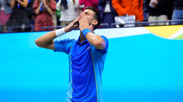 Novak Djokovic puts two hands to his mouth to blow a kiss to the audience